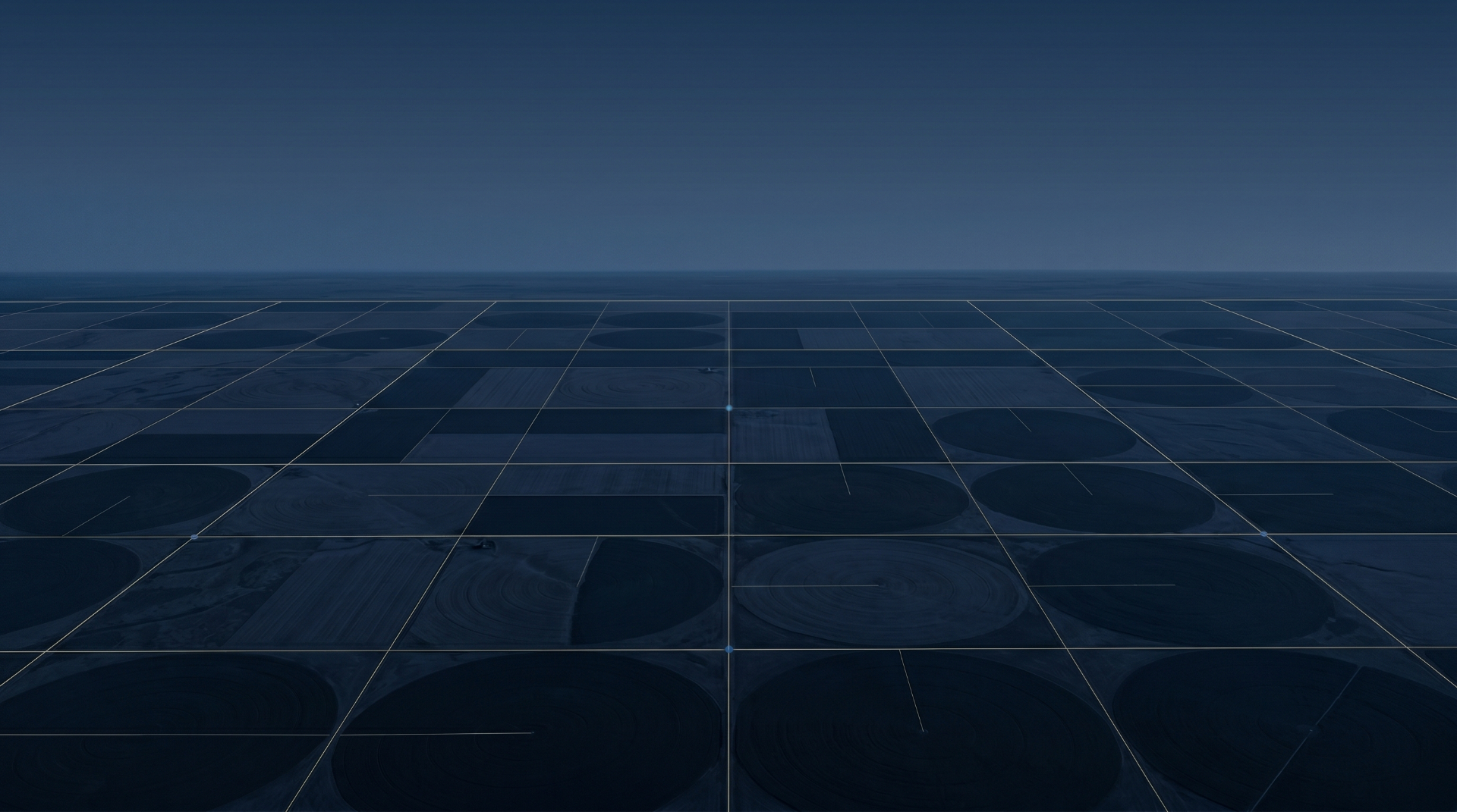Aerial view at dusk of geometrically organized farmland with faint surveyed grid lines.